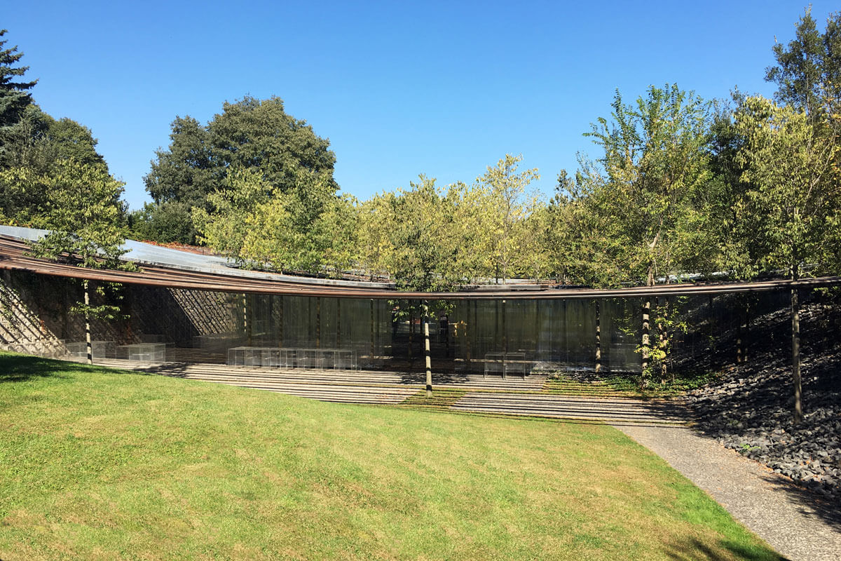 Gently curved canopy flowing over the landscape with vertical blinds of translucent plastic