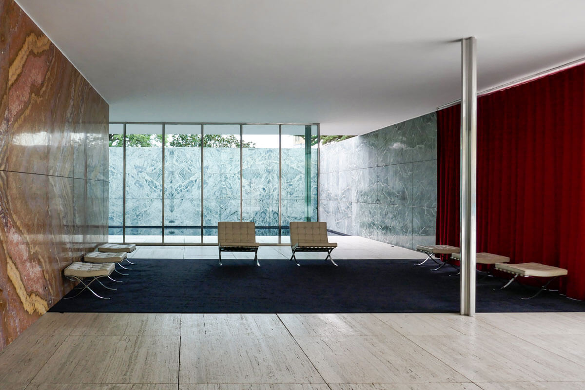 Reception space of Mies van der Rohe's Barcelona pavilion with golden onyx wall, black carpet and red curtain