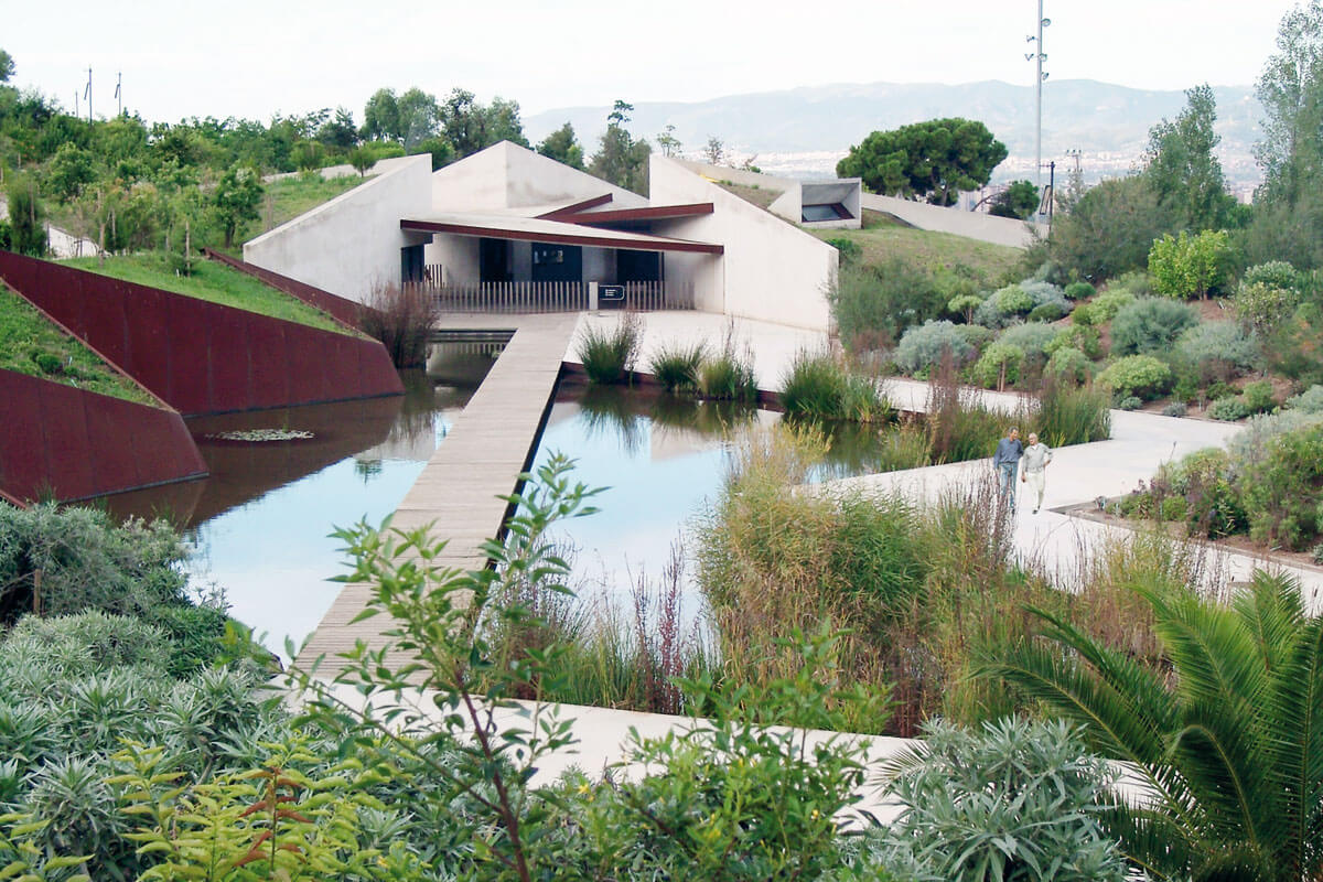 Entrance building to Barcelona's botanical garden with fractured geometry and pond, featured on architecture tour Montjuïc