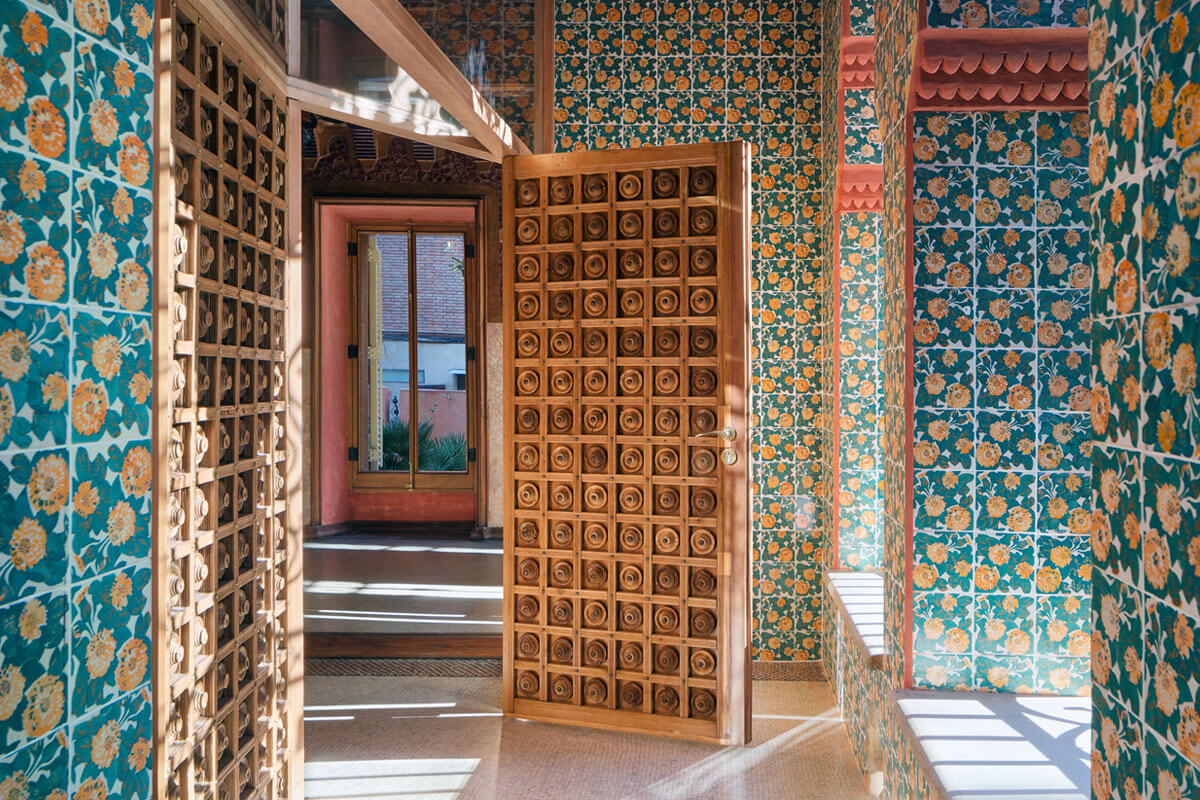 Entrance area of Casa Vicens featuring colourful floral pattern ceramic wall tiles and wooden door