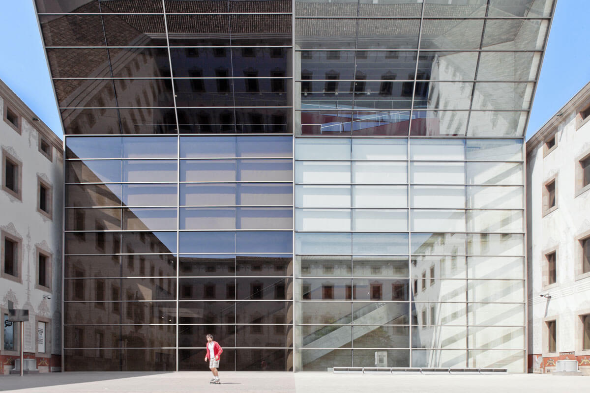 Angled facade with mirror glazing closing u-shaped courtyard and reflecting the surrounding buildings