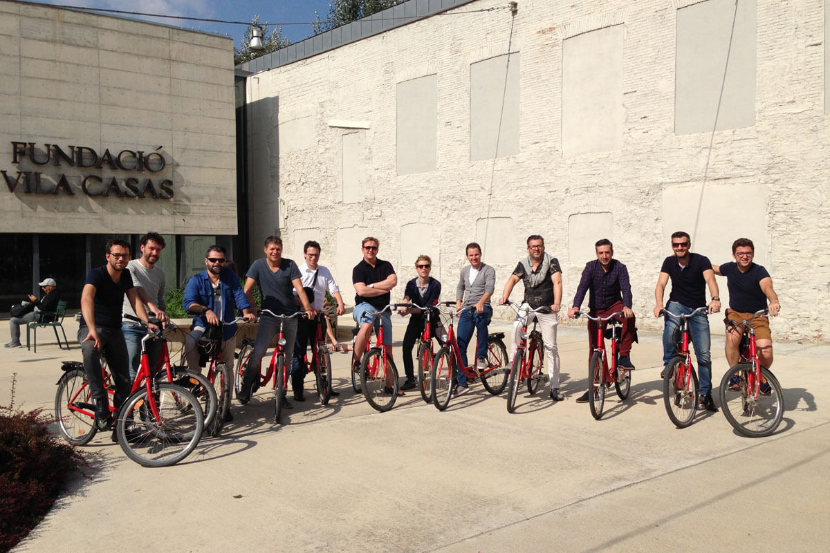 Group of architects on bicycles posing for a photo in the minimalist courtyard of Barcelona's Can Framis Museum