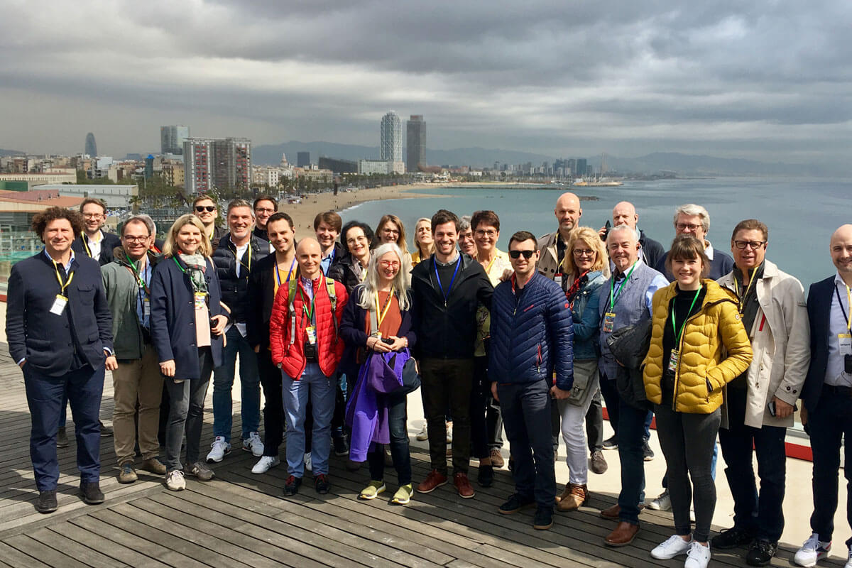 Group of architects posing on rooftop terrace in front of the Mediterranean and Barcelona's beachline