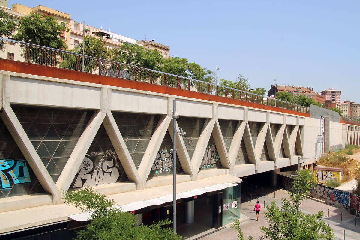 Urban green space on top of concrete truss structure enclosing an elevated metro track